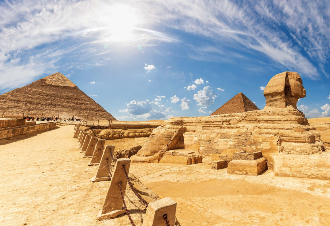 Front view of the Great Sphinx of Giza with the pyramids in the background under a clear sky